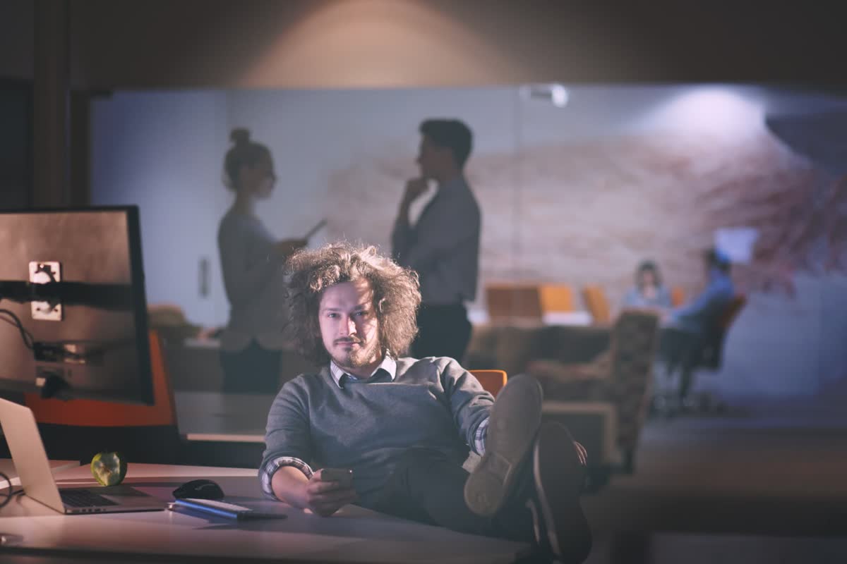 Creative professional relaxed at a dual-monitor editing desk in a modern office
